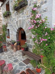 伊萨瓦Casa rural ELURKOIA的石头建筑,有长凳和粉红色玫瑰