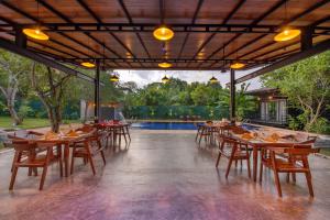 锡吉里亚Atha Resort的一间带木桌和椅子的餐厅以及游泳池