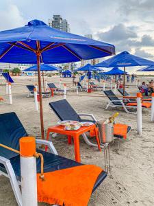 卡塔赫纳Hotel Cabreromar By GEH Suites的海滩上的一组椅子和遮阳伞
