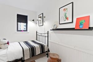伦敦Modern 2 Bedroom Apartment in Hoxton的一间卧室配有一张床,墙上挂着一些图片