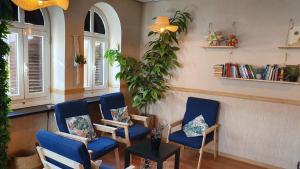 马德里GREEN Hostel MADRID GRAN VIA的一间设有蓝色椅子和植物的等候室