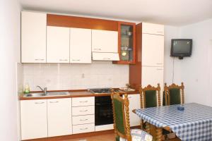 拉茨斯切Apartments by the sea Kneza, Korcula - 167的厨房配有白色橱柜、桌子和电视。