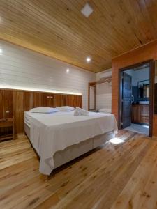 IbiramaPousada Scursel的一间卧室设有一张大床,铺有木地板