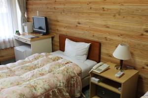 本宫川汤绿屋山水馆酒店的一间卧室配有一张床和一张书桌及电视