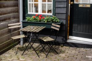 兹沃勒The Cabin at Zwolle Centraal的两把椅子和一张桌子,位于带窗户的房子前