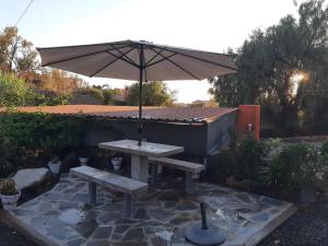 蓬塔戈尔达Casa roko的一张带雨伞和长凳的野餐桌