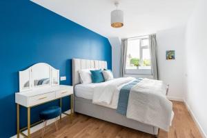 牛津Dunstan House Luxury Holiday Home with free parking的一间蓝色和白色的卧室,配有一张床和镜子