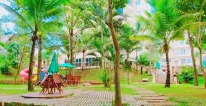 热河市Thermas Paradise Apart的一个带桌子和遮阳伞以及棕榈树的公园