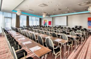 慕尼黑慕尼黑市南莱昂纳多酒店的一间会议室,配有桌椅和屏幕