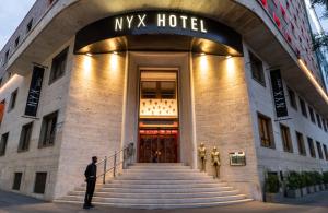 米兰NYX Hotel Milan by Leonardo Hotels的站在一个神话酒店前的人