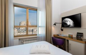 米兰NYX Hotel Milan by Leonardo Hotels的客房设有床、书桌和窗户。