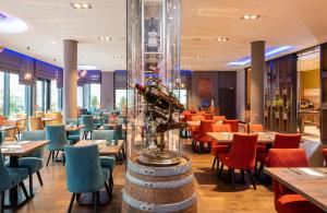 巴特克罗伊茨纳赫Leonardo Hotel Bad Kreuznach的配有桌椅和一瓶葡萄酒的餐厅
