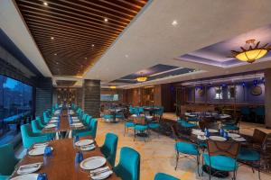 加济阿巴德Radisson Blu Kaushambi Delhi NCR的餐厅设有木桌和蓝色椅子