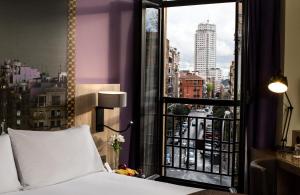马德里马德里市中心莱昂纳多酒店的一间卧室设有一张床和一个享有城市景观的窗户。