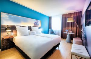 曼海姆NYX Hotel Mannheim by Leonardo Hotels的酒店客房设有一张大床和蓝色的墙壁。