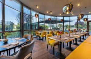 维罗纳Leonardo Hotel Verona的餐厅设有桌椅和大窗户。