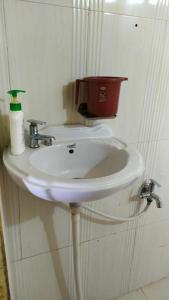 OsiānOsian Dhana Ram Ki Dhani Home Stay Osian的白色浴室水槽,墙上装有红色桶