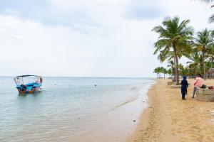 帕西库达Gnanam Holiday Inn的两个人站在海滩上,在水中划船