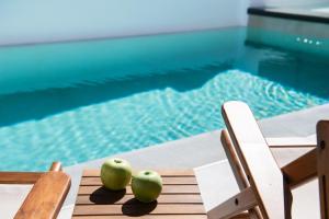 雷夫卡达镇SunilioS Apartments Lefkada的两只苹果坐在泳池旁的桌子上