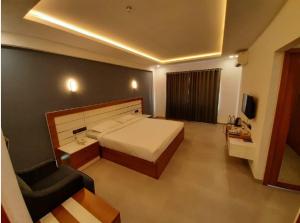 科泽科德Ashirvad Lawns Hotel & Convention Centre的一间卧室配有一张床、一张沙发和一把椅子