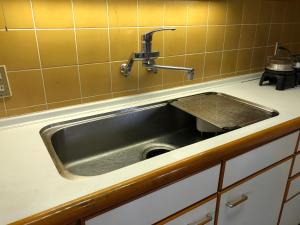 飞騨市Cool-Villa 飛騨リゾート的厨房里有一个不锈钢水槽,有黄色的瓷砖
