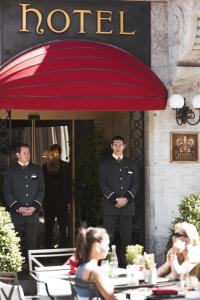 日内瓦白鹤酒店的身着制服的两名男子站在红伞下