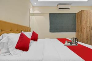 孟买Hotel Sunrise Juhu的一间卧室配有一张带红色枕头的大床