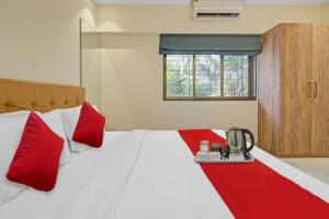孟买Hotel Sunrise Juhu的一间卧室配有一张带红色枕头的大床