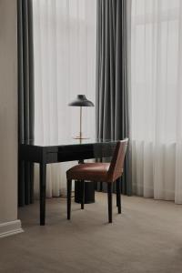 哥本哈根Avenue Hotel Copenhagen by Brøchner Hotels的书桌、椅子、灯和窗帘