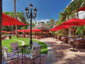 拉克鲁斯东方植物园水疗花园酒店的一个带桌椅和红色遮阳伞的庭院