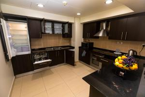 多哈帝国套房公寓的厨房配有黑色橱柜和柜台上的一碗水果