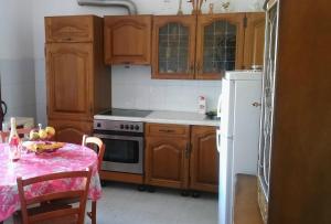 普特尼科维奇Apartments by the sea Luka Dubrava, Peljesac - 13632的厨房配有木制橱柜、桌子和白色冰箱。
