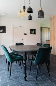 HarelbekeFarmhouse Hoeve Den Ast 5 separate bedrooms with bathrooms的一间带木桌和绿色椅子的用餐室