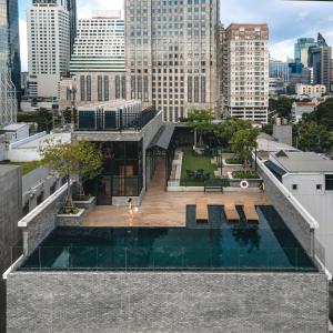 曼谷The Coach Hotel Sukhumvit - Asok BTS Bangkok by Compass Hospitality的城市中心一座带游泳池的建筑