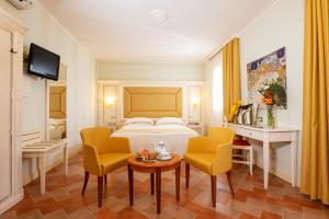 普林斯皮纳·特拉Antica Fornace Relais by La Principina的酒店客房配有一张床、两把椅子和一张桌子