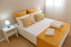 巴塔拉The Modern 1385 Apartment的白色的床、橙色和白色枕头以及桌子