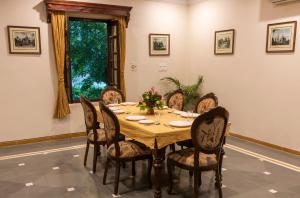 焦特布尔Hanuwant Niwas Jodhpur的一间带木桌和椅子的用餐室