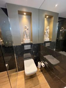 莱顿Het Waterhof的一间带卫生间的浴室和墙上的两座雕像