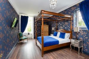 RainhullRainHill Hall Hotel的一间卧室配有天蓬床和蓝色壁纸