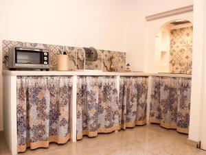 马丁纳弗兰卡Casa Vacanze L'essenziale的厨房配有带窗帘的台面和微波炉