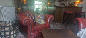 库姆马丁The Poplars Guest House的客厅配有红色皮革椅子和桌子