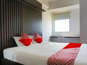 ParungdengdekOYO 91593 San San Rooms Apartment Gunung Putri Square的一间卧室配有一张带红色和白色枕头的大床