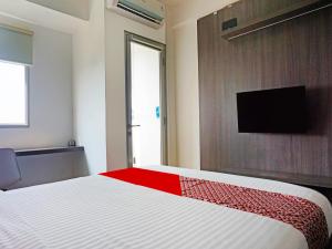 ParungdengdekOYO 91593 San San Rooms Apartment Gunung Putri Square的一间卧室配有一张床,墙上配有电视