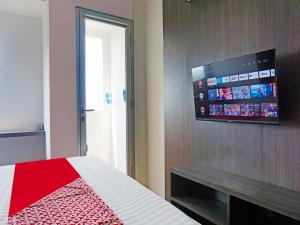 ParungdengdekOYO 91593 San San Rooms Apartment Gunung Putri Square的卧室配有一张壁挂式平面电视的床。