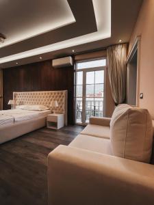 地拉那Amansar Boutique Hotel的一间卧室设有两张床、一张沙发和一个窗口