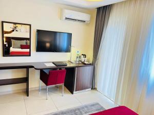 科纳克里Souaré Premium Hôtel的客房设有一张桌子、一台电视和一张床