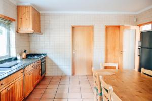 维拉·诺瓦·达·塞尔维尔Just Like Home - Casa do Sobreiro Velho em Cerveira的厨房配有木制橱柜和木桌。
