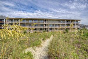 默特尔比奇BEAUTIFUL BEACHFRONT-Oceanfront First Floor 2BR 2BA Condo in Cherry Grove, North Myrtle Beach! RENOVATED with a Fully Equipped Kitchen, 3 Separate Beds, Pool, Private Patio & Steps to the Sand!的海滩上的建筑,前面有一条小径