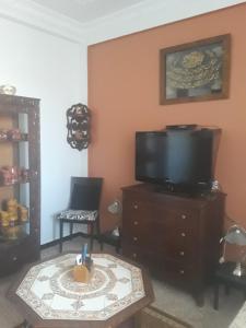 阿尔及尔Bel Appartement Kouba Centre的客厅配有电视和带蜡烛的桌子。