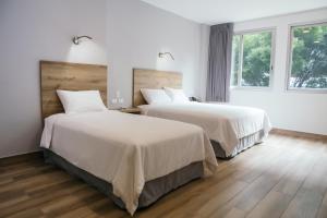 瓜亚基尔The Park Hotel的配有白色墙壁和木地板的客房内的两张床